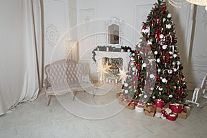 Christmas living room with a fireplace, sofa, Christmas tree and gifts. Beautiful New Year decorated classic home interior.