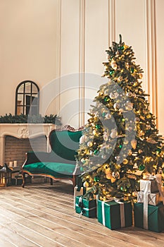 Christmas living room with a fireplace, sofa, Christmas tree and gifts. Beautiful New Year decorated classic home interior. Winter
