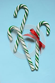 Christmas lollipops lied evenly in row on blue background. Flat lay and top view