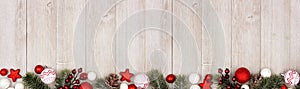 Christmas long border banner with red and white ornaments and branches, top view on a gray wood background