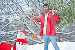 Christmas lumberjack with axe and Christmas tree. Bearded Man cutting Christmas tree. Woodcutter with axe in the winter