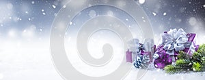 Christmas luxury purple gifts in snow and abstract snowy atmosphere photo