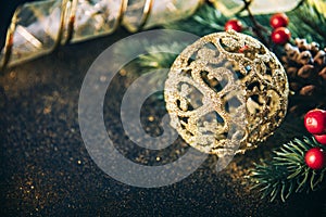 Christmas luxury still life with golden christmas ornament, fir tree and gold ribbon on dark vintage table. Closeup of luxury home