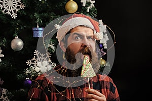 Christmas man with beard on surprised face and lollipop.