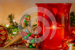 Christmas mantelpiece with red and green  ornaments and red glass candle holder