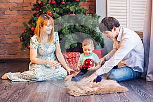 Christmas, x-mas, family, people, happiness concept - happy parents playing with cute baby boy