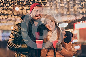 Christmas x-mas spirit celebration. Boyfriend hug his girlfriend hold eggnog hot beverage mug under shine evening lights
