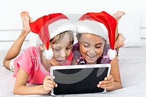 christmas, x-mas, winter, happiness concept - two adorable curly girls playing with tablet pc