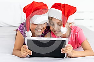 christmas, x-mas, winter, happiness concept - two adorable curly girls playing with tablet pc