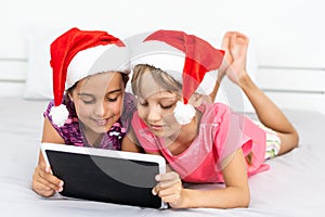 christmas, x-mas, winter, happiness concept - two adorable curly girls playing with tablet pc