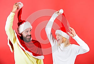 Christmas masquerade or karnival concept. Man with beard and woman in santa hat with pompon red background. Couple