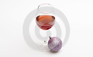 Christmas menu concept. Wineglass with red liquid or wine and christmas ball ornament isolated on white background