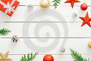 Christmas minimal composition. Frame made of Christmas decorations, red stars, gift box, balls, cones, fir tree branches on wooden photo