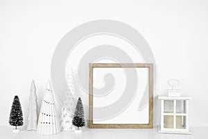 Christmas mock up with wooden frame, lantern and tree decor on a white shelf against a white wall