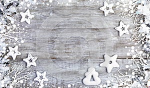 Christmas mockup. Frame of white Christmas stars, gingerbreads, twigs, tinsel and snow on white wooden background.