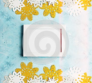 Christmas mockup: White photoframe with white and golden snowflakes on light blue background. Winter, New year concept
