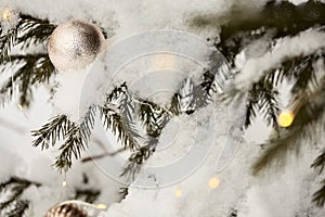 Christmas mood. beautiful golden Christmas decoration on a snow-covered branch of a Christmas tree and a beautiful garland with