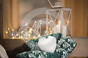 Christmas mood with snowball in shape of heart in hands with mittens  outdoor candle holder with burning candle