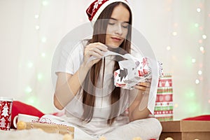 Christmas mood. Young woman opens new year`s gifts in bed