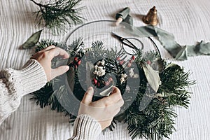 Christmas moody still life. Closeup of women hands crafting advent floral hoop wreath. Garland of fir, eucalyptus. Pine
