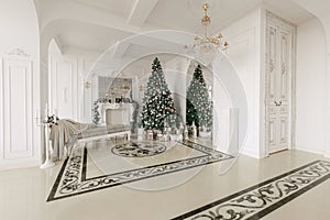 Christmas morning. classic luxurious apartments with a white fireplace, decorated christmas tree, sofa, large windows