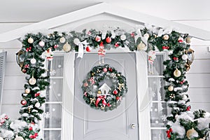 Christmas morning. house entrance decorated for holidays. Christmas decoration. garland of fir tree branches and lights