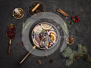 Christmas mulled red wine with the addition of spices and citrus fruits in a small vintage copper pan on a black background, top