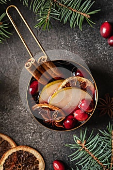 Christmas mulled red wine with spices, cranberry and fruits on brown textured background. Traditional festive hot drink