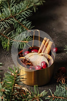 Christmas mulled red wine with spices, cranberry and fruits on brown textured background. Traditional festive hot drink