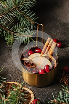 Christmas mulled red wine with spices, cranberry and fruits on brown textured background. Traditional festive hot drink