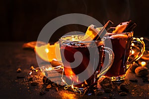 Christmas mulled red wine with spices and fruits on wooden rustic table. Traditional Christmas hot drink in festive light table