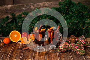 Christmas mulled wine with fruits and spices on wooden table. Xmas decorations in background. Two glasses. Winter warming drink r