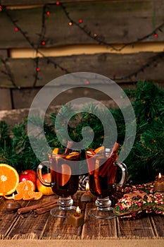 Christmas mulled wine with fruits and spices on wooden table. Xmas decorations in background. Two glasses. Winter warming drink r