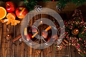 Christmas mulled wine with fruits and spices on wooden table. Xmas decorations in background. Two glasses. Winter warming drink r