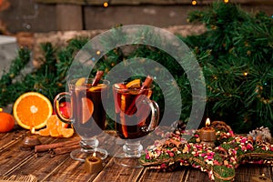 Christmas mulled wine with fruits and spices on wooden table. Xmas decorations in background. Two glasses. Winter warming drink r