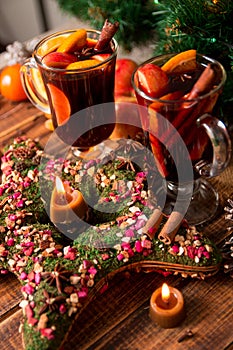 Christmas mulled wine with fruits and spices on wooden table. Xmas decorations in background. Two glasses. Winter warming drink r