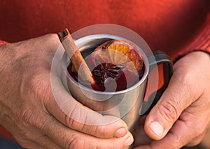 Christmas mulled wine in Hand of old man, delicious holiday like parties with orange cinnamon star anise spices. Traditional hot