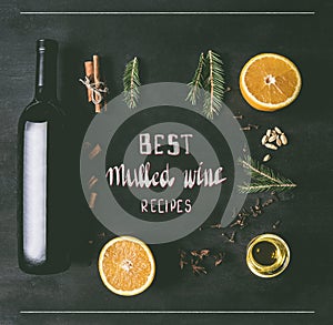 Christmas mulled wine preparation, a bottle of wine, oranges, seasonings and spices, anise and cinnamon, on a black wooden