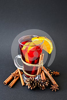 Christmas mulled wine with spices and orange on dark black background. Selective focus. Anise stars and cinnamon sticks. Christmas