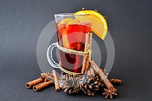 Christmas mulled wine with spices and orange on dark black background. Selective focus. Anise stars and cinnamon sticks. Christmas