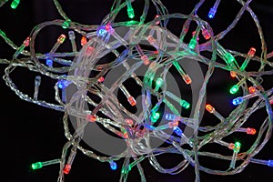 Christmas multicolor lights on a black background. Electric lights. Decorative garland. Bulbs on the wire