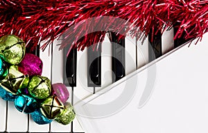 Christmas music concept. Blank paper on the piano with jingle bells and red tinsel