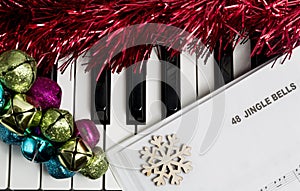 Christmas music concept. Printed music on the piano with jingle bells, snowflake and spangle