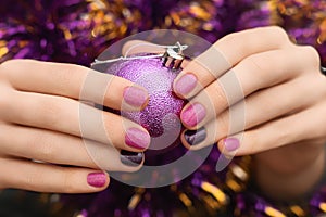 Christmas nail design. Female hands with pink and brown nail manicure. Famale hold xmas toy orb