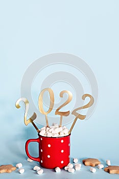 Christmas or New Year 2022 creative concept. Hot chocolate in red mug and golden numbers 2022, copy space