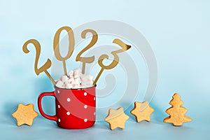 Christmas or New Year 2023 creative concept. Hot chocolate in red mug and golden numbers 2023, copy space
