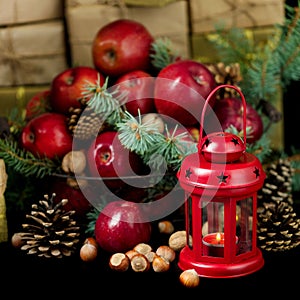 Christmas and New year. Apples with pine cones and nuts in a basket with fir branches. Gifts and candles.