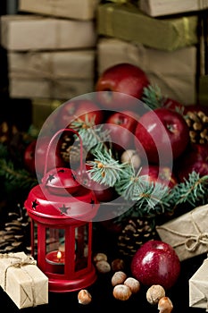 Christmas and New year. Apples with pine cones and nuts in a basket with fir branches. Gifts and candles.