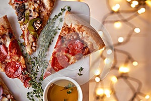 Christmas and New Year atmosphere. Hot Italian pizza with melting tomato, pepperoni and cheese on a white marbel cutting