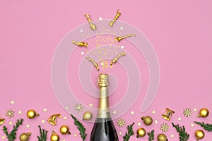 Christmas and New Year background. Champagne bottle, golden christmas balls, festive ribbons, fir branches, star confetti on pink